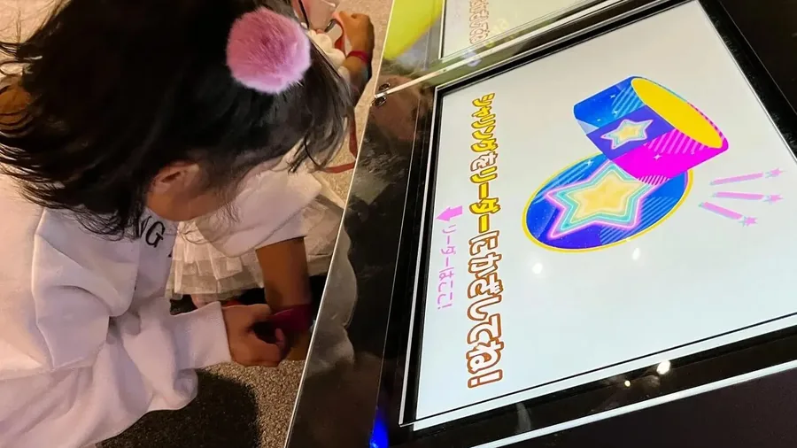 シャリングステーションの画面をタッチして、サプリを交換している子ども